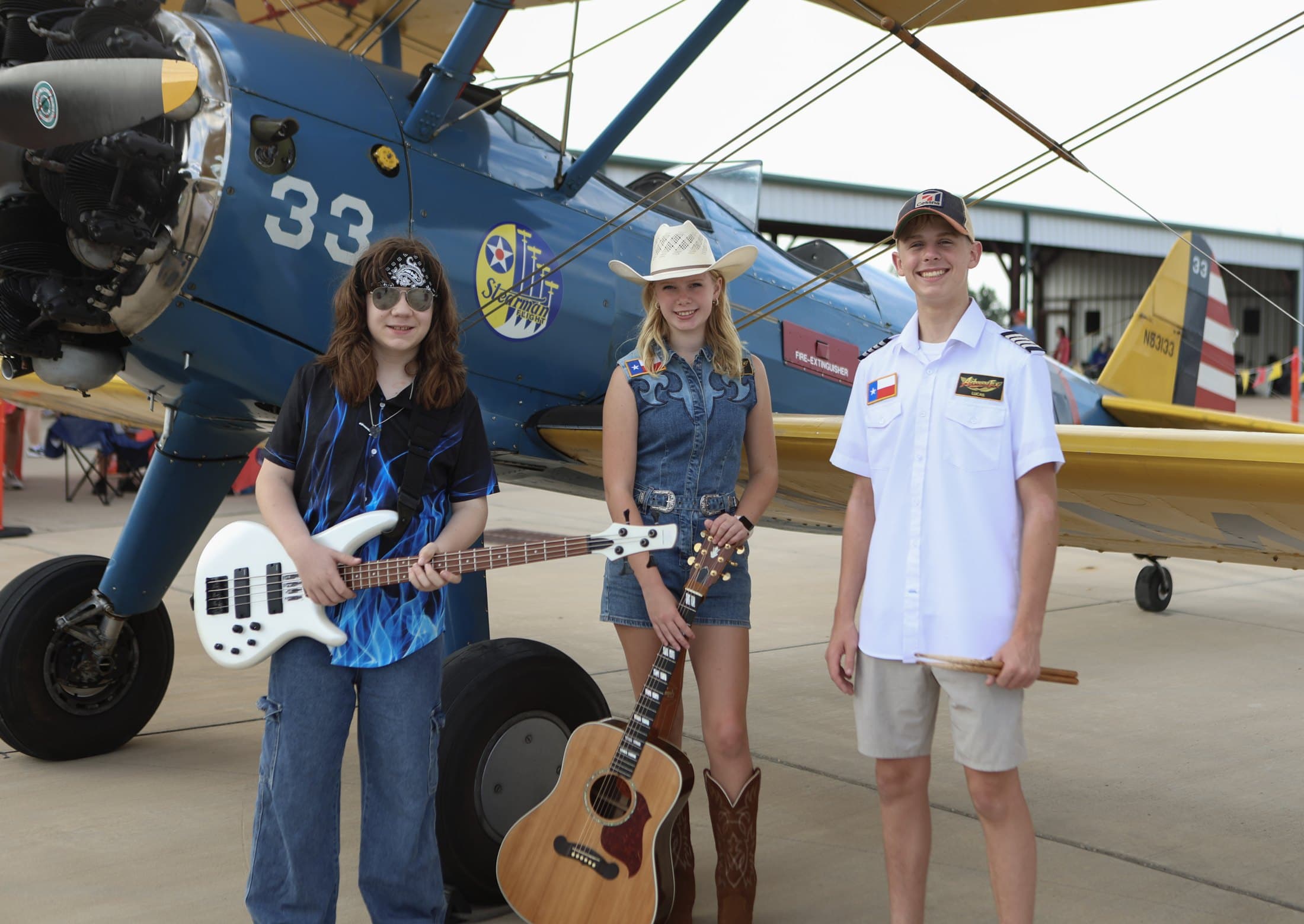 Airbourne Tex with a vintage biplane at an Airplanes & Coffee fly-in in August 2026. From left: Jaxton Weatherly, Maryanne Hilton and Lucas Rehl. Photo: Jacey Rae Photography